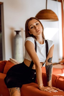 Black-Mango teases solo on orange couch spreading legs and stripping top in bedroom light