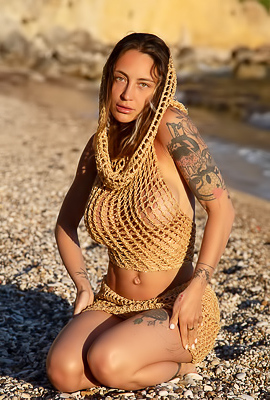Alba Sheds A Gold Crochet Net On A Pebble Beach